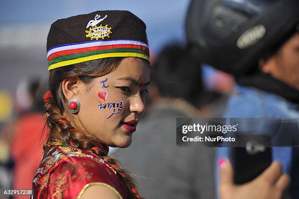 Girl in a traditional attire takes pictures from mobile phone during celebration of Sonam Losar festival or Lunar New Year, which occurs around the...