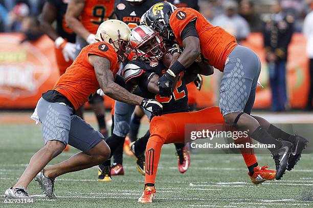 Taywan Taylor of the South team is tackled by John Johnson of the North team and Desmond King during the first half of the Reese's Senior Bowl at the...