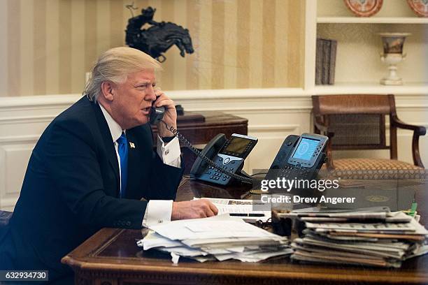 President Donald Trump speaks on the phone with Australian Prime Minister Malcolm Turnbull in the Oval Office of the White House, January 28, 2017 in...