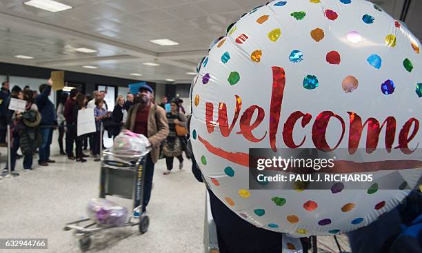 Protesters gather at the international arrivals area of the Washington Dulles International Airport on January 28 in Sterling, Virginia. US President...