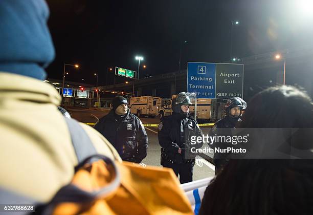 Police officers stand guard as protestors rally during a demonstration against the new immigration ban issued by President Donald Trump at John F....