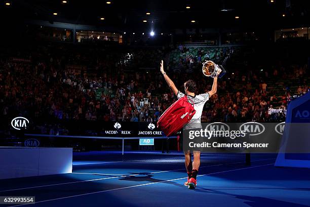 Roger Federer of Switzerland walks off court with the Norman Brookes Challenge Cup after winning the Men's Final match against Rafael Nadal of Spain...