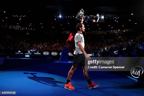 Roger Federer of Switzerland walks off court with the Norman Brookes Challenge Cup after winning the Men's Final match against Rafael Nadal of Spain...