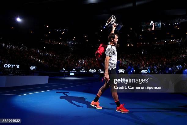 Roger Federer of Switzerland walks off court with the Norman Brookes Challenge Cup after winning the Men's Final match against Rafael Nadal of Spain...