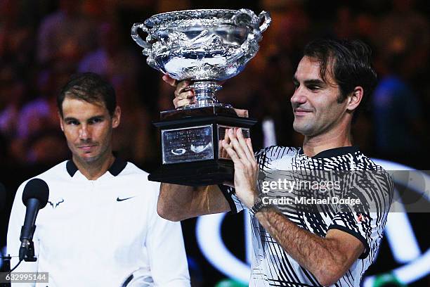 Defeated Raphael Nadal of Spain reacts as Roger Federer of Switzerland celebrates with the Trophy after winning in the Men's Final match against on...