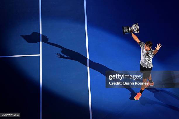 Roger Federer of Switzerland walks off court with the Norman Brookes Challenge Cup after winning the Men's Final match against Rafael Nadal of Spain...