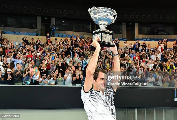 Roger Federer of Switzerland celebrates with fans in Margaret Court Arena as he holds the Norman Brookes Challenge Cup after winning the Men's Final...