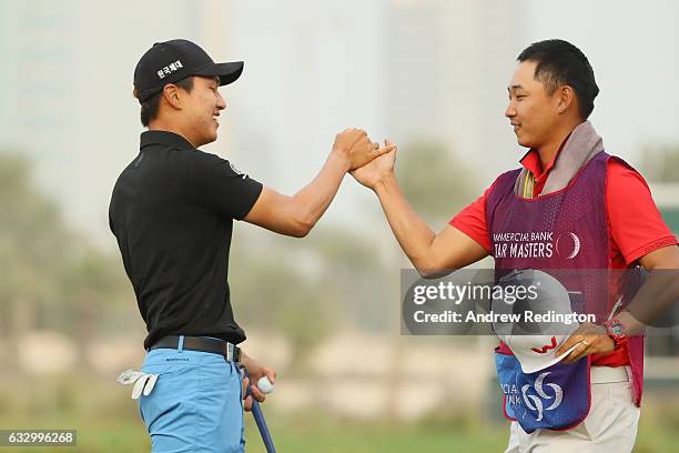 Jeunghun Wang of South Korea celebrates his victory in the playoff with caddie Dongwoo Ko during the fourth round of the Commercial Bank Qatar...