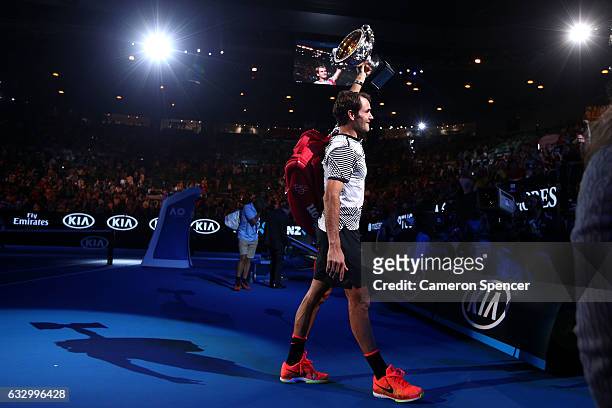 Roger Federer of Switzerland walks off court with the Norman Brookes Challenge Cup after winning the Men's Final match against Rafael Nadal of Spain...