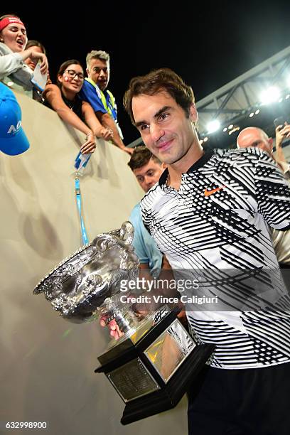 Roger Federer of Switzerland walks off Margaret Court Arena as he holds the Norman Brookes Challenge Cup after winning the Men's Final match against...