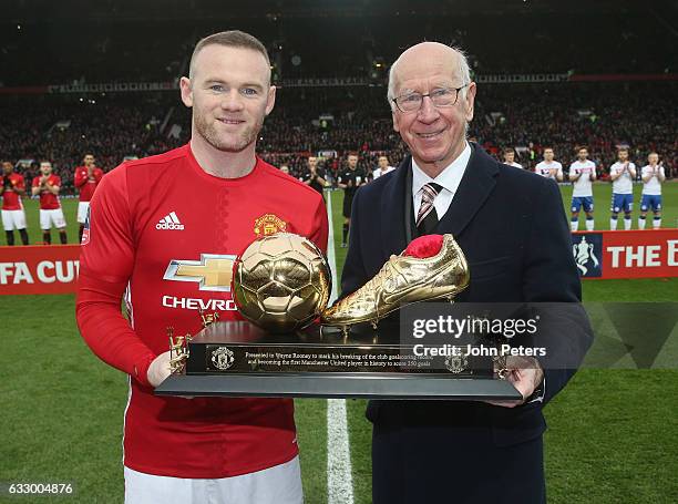 Wayne Rooney of Manchester United is presented with a golden boot by Sir Bobby Charlton to mark his 250th Manchester United goal, which saw him break...