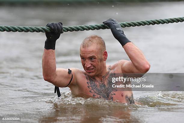 Competitor holds onto a rope as he wades through deep water during the Tough Guy Challenge at South Perton Farm on January 29, 2017 in Telford,...