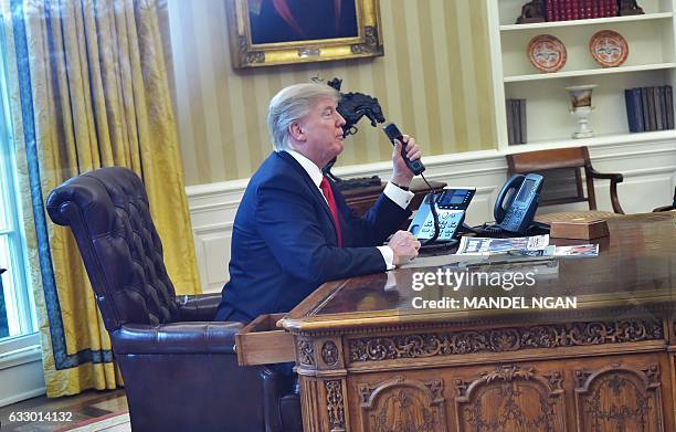 President Donald Trumpseen through an Oval Office window speaks on the phone to King Salman of Saudi Arabia from the Oval Office of the White House...