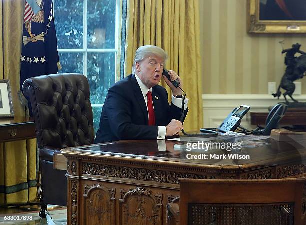 President Donald Trump is seen through a window speaking on the phone with King of Saudi Arabia, Salman bin Abd al-Aziz Al Saud, in the Oval Office...
