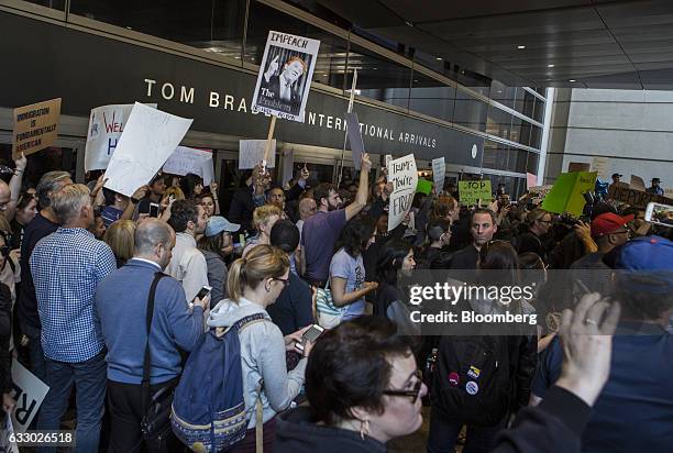 Demonstrators hold signs outside Los Angeles International Airport protesting U.S. President Donald Trump's executive order blocking visitors from...