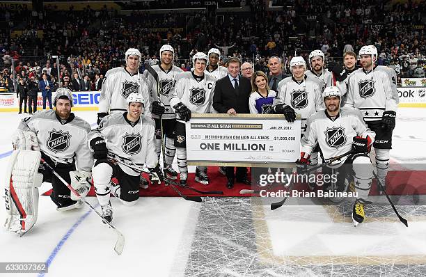 Deputy NHL Commissioner Bill Daly and anthem singer Courtney Daniels present the one million dollar winner's check to members of the Metropolital...