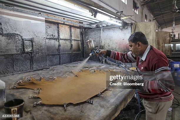 Worker uses a spray gun to treat a sheet of leather at the Jalandhar Leather Pvt. Tannery in Jalandhar, Punjab, India, on Saturday, Jan. 21, 2017....