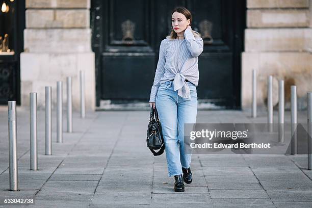 Amelie lloyd wears Newlook black shiny boots, Levi's blue denim boyfriend jeans pants, a Newlook blue and white striped shirt with a knot, a...