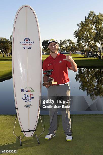 Jon Rahm of Spain poses with his trophy and surfboard on the 18th hole during the final round of the Farmers Insurance Open at Torrey Pines South...