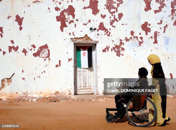 Sahrawi assistant pulls the wheelchair of landmine victim Jazna Lehni on March 1, 2011 at the landmines victims center "Martyr El Sherif", near the...