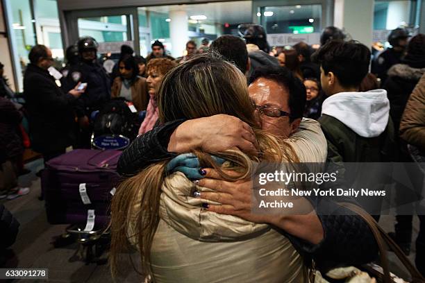 Passenger is greeted by family members at John F. Kennedy International Airport as protestors gathered to protest President Donald Trump's refugee...