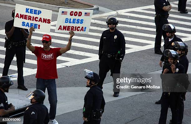 Lone supporter of President Trump and Vice President Pence is protected by police while a large group of people continue to protest President Donald...