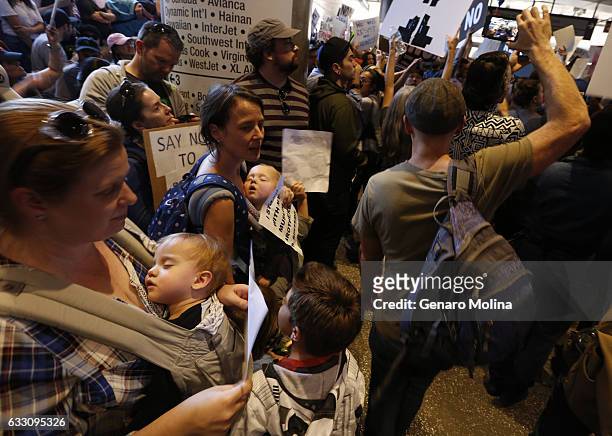 Amanda Shipman, from left, holds her son Zander Mora-Shipman, and Ashley Potenza, holds her son Jude while joining people who continue to protest...