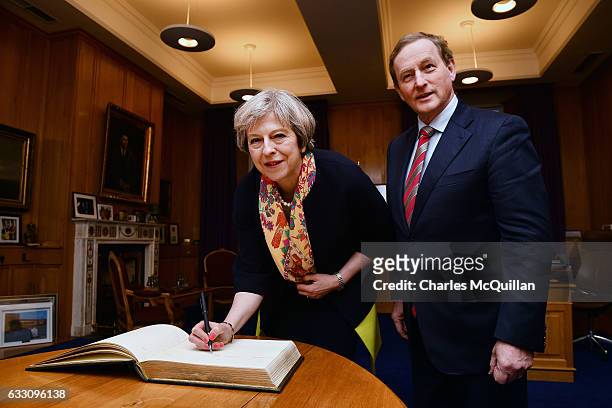 British Prime Minister Theresa May signs the visitors book watched by Irish Taoiseach Enda Kenny at Government Buildings on January 30, 2017 in...