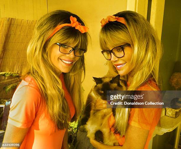 Shane Barbi and Sia Barbi of The Barbi Twins pose for a portrait with a cat in circa 1995.