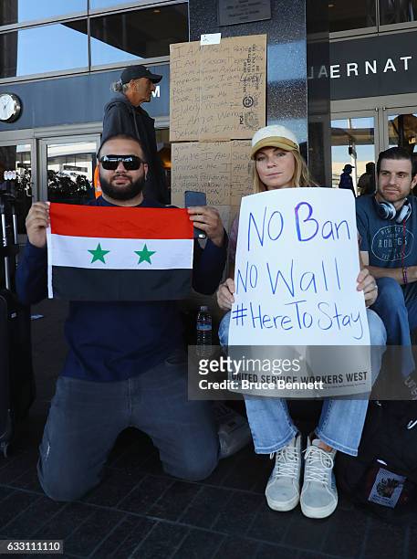 Syrian born Los Angeles resident Adam Afara poses with the Syrian flag and joins with Ryan James who was protesting Donald Trump's travel ban greet...