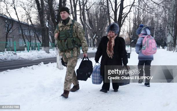 An Ukrainian serviceman help an elderly woman to carry her belongings to a tent set to warm local residents of town of Avdiivka ,Donetsk region after...