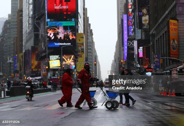 Workers spread salt along streets during a snowfall at Times Square in New York, USA on January 31, 2017.