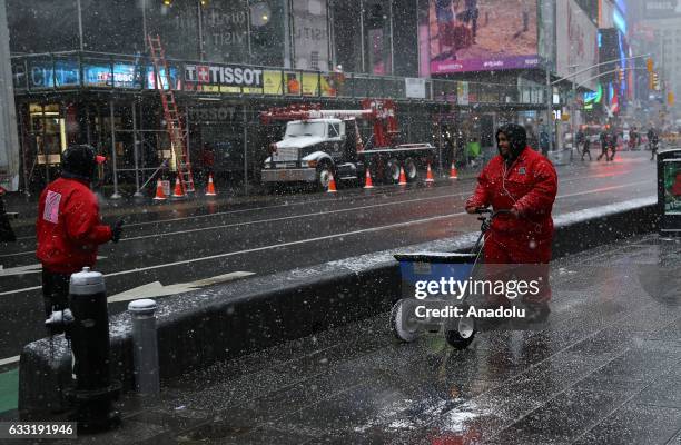 Workers spread salt along streets during a snowfall at Times Square in New York, USA on January 31, 2017.