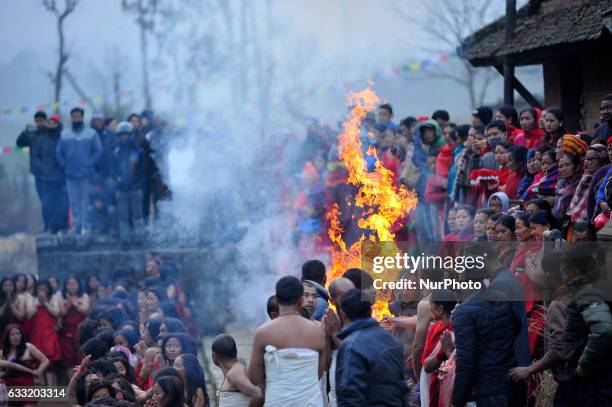 Nepalese Devotees warm themselves in a fire before taking ritual bath in Triveni River during Madhav Narayan Festival or Swasthani Brata Katha...