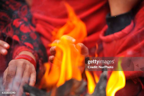 Nepalese Devotees warm themselves in a fire after taking ritual bath in Triveni River during Madhav Narayan Festival or Swasthani Brata Katha...