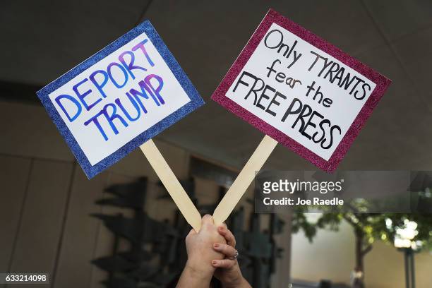 Protester holds up signs as she gathers with others against Miami-Dade Mayor Carlos Gimenez's decision to abide by President Donald Trump's order to...