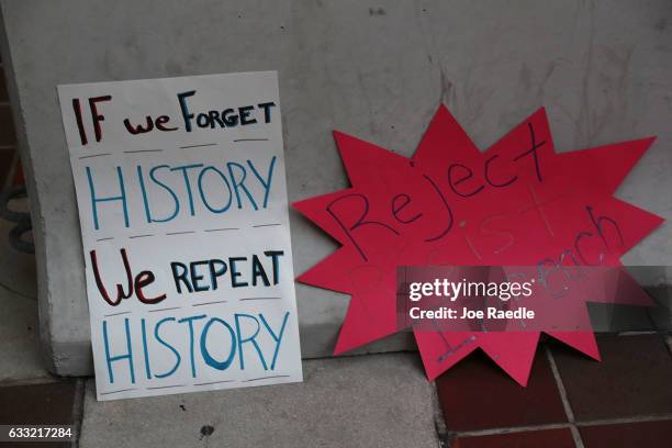 Protest signs are seen as people gather against Miami-Dade Mayor Carlos Gimenez's decision to abide by President Donald Trump's order to effectively...