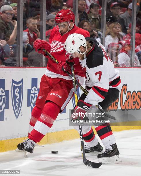 Andreas Athanasiou of the Detroit Red Wings battles for the puck with Jon Merrill of the New Jersey Devils during an NHL game at Joe Louis Arena on...