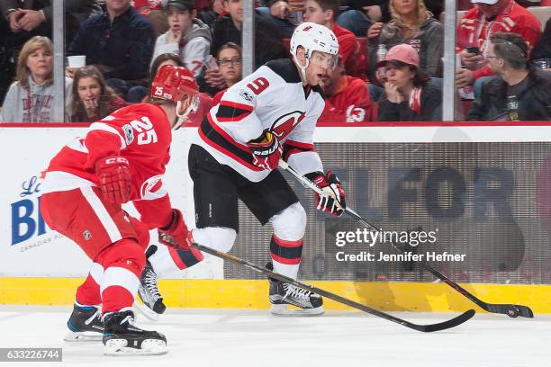 Taylor Hall of the New Jersey Devils skates with the puck along the boards followed by Mike Green of the Detroit Red Wings during an NHL game at Joe...