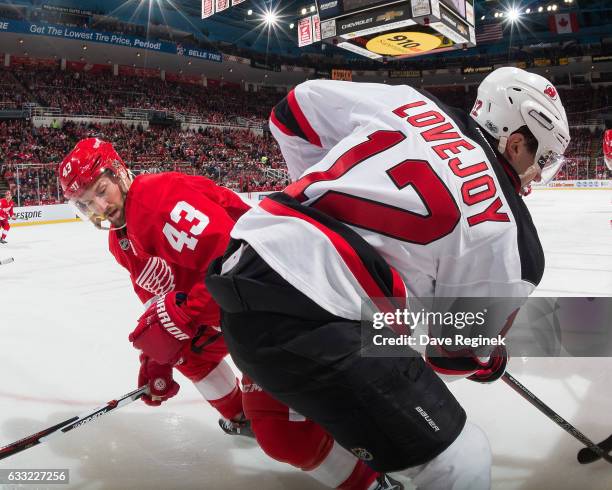 Ben Lovejoy of the New Jersey Devils battles along the boards with Darren Helm of the Detroit Red Wings during an NHL game at Joe Louis Arena on...