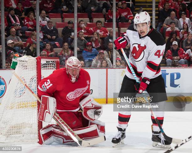 Goaltender Jared Coreau of the Detroit Red Wings follows the puck as Miles Wood of the New Jersey Devils looks for the rebound during an NHL game at...