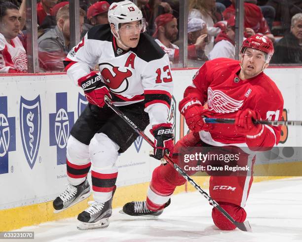 Michael Cammalleri of the New Jersey Devils skates along the boards followed by Xavier Ouellet of the Detroit Red Wings during an NHL game at Joe...