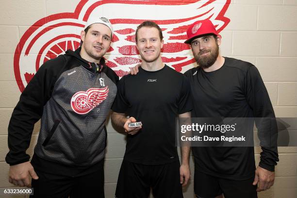 Nick Jensen of the Detroit Red Wings holds the puck from his first NHL goal with teammates Xavier Ouellet and Henrik Zetterberg after an NHL game...