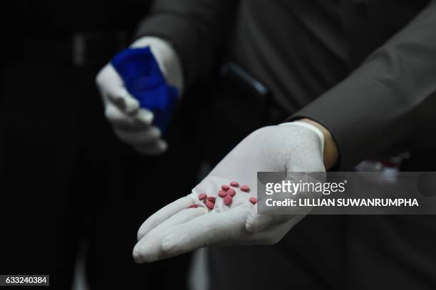Police officer displays "yaba" tablets, or methamphetamine mixed with caffeine, for the media in front of the Narcotics Suppression Division in...
