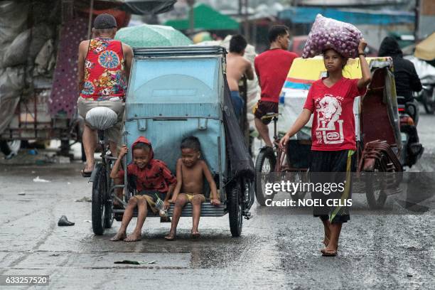 Boys hitch a ride on a pedicad at the Divisoria market in Manila on February 1, 2017. / AFP PHOTO / NOEL CELIS