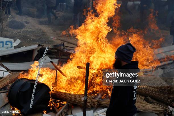 An Israeli settler stands next to burning furniture during scuffle with security forces at the Amona outpost, northeast of Ramallah, on February 1,...