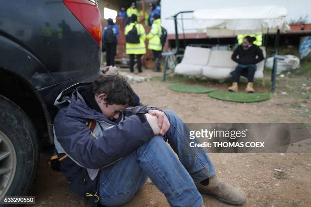Young Jewish settler sits crying by a car as Israeli security forces clear the wildcat Amona outpost, northeast of Ramallah, on February 1 in line...