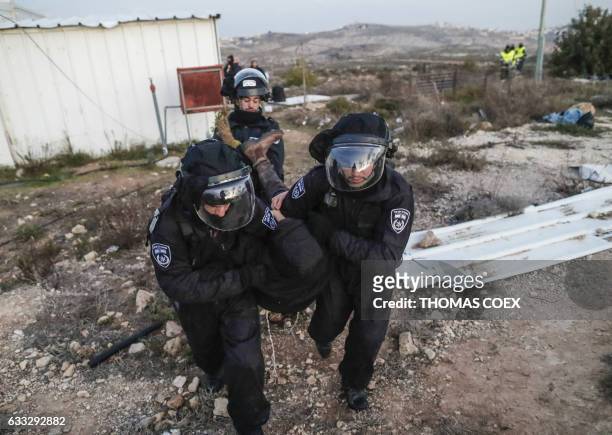 Israeli security forces carry a settler away as they evict hardline residents from the wildcat Amona outpost, northeast of Ramallah, on February 1 in...