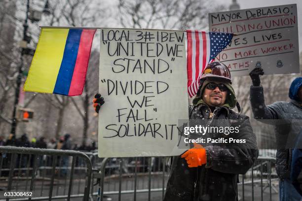 Man holding a placard during the protest. Over 30,000 members of New York City's Building Trades walked off their jobs, to rally outside of City...