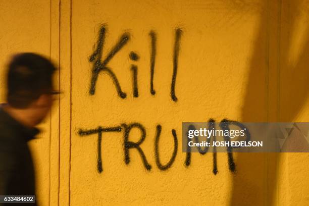 Man looks at graffiti during a protest in Berkeley, California on February 1, 2017. - Violent protests erupted on February 1 at the University of...